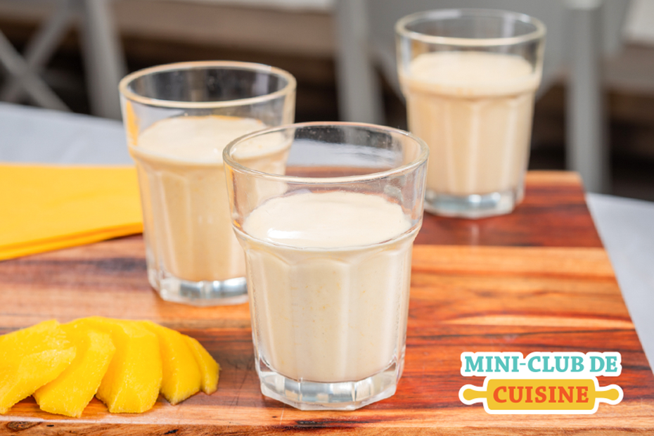 Lassi à la mangue dans un verre et une mangue tranchée à côté 