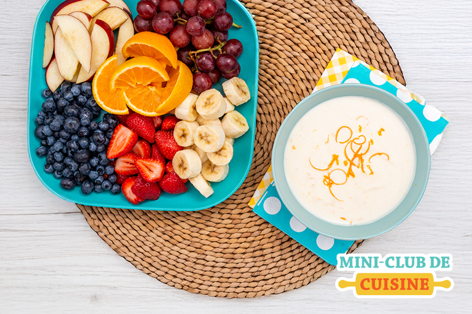 trempette à l'orange dans un bol avec une assiette de fruits frais à côté sur une table. Logo Mini-club de cuisine